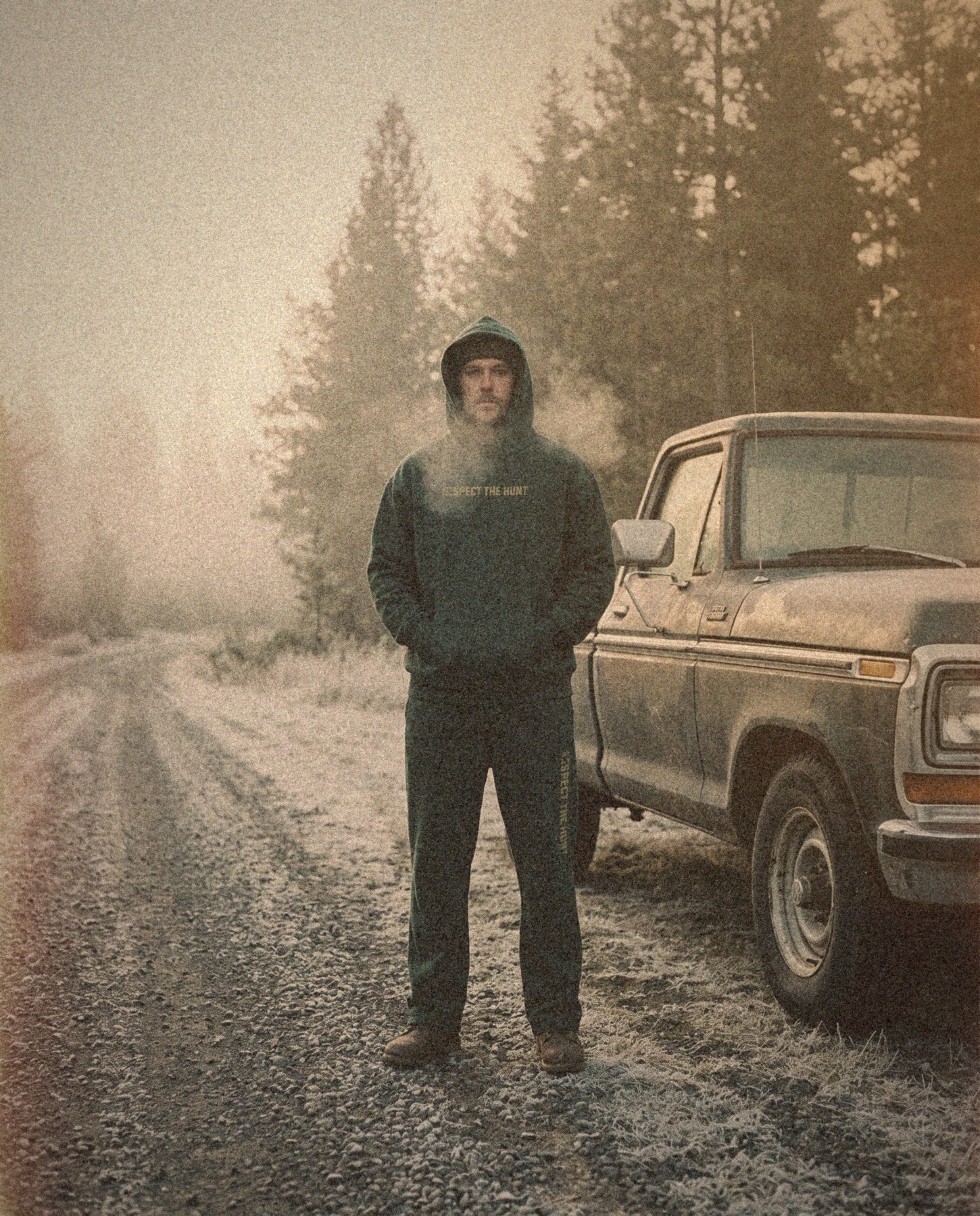 Matching heavyweight hoodie and sweatpants on a frosty road at first light, grainy 35mm film